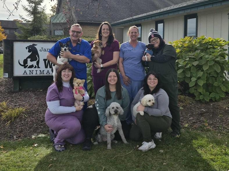The Woodland Animal Hospital team with their dogs in front of the hospital sign